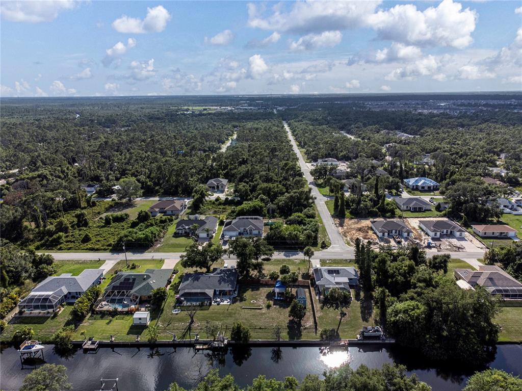 An aerial view shows waterfront homes along a canal with surrounding wooded areas and roads — 17221 NIXON AVENUE, PORT CHARLOTTE, FL