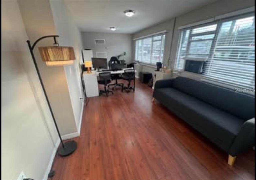 A home office features wood-look flooring, a dark sofa, a desk, and a floor lamp — 531 N US HIGHWAY 17 92, LONGWOOD, FL