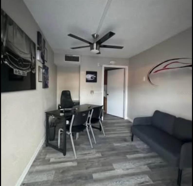 A room with gray wood-look flooring, a desk with chairs, a sofa, and a ceiling fan — 531 N US HIGHWAY 17 92, LONGWOOD, FL