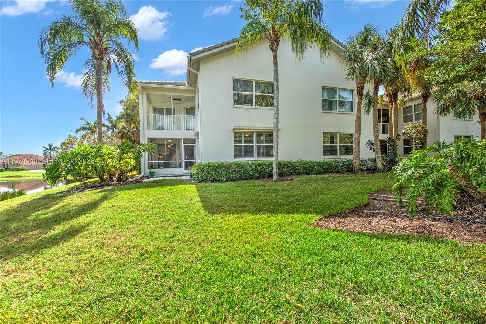 The exterior of a two-story residential building features a screened-in patio and palm trees — 8385 Whisper Trace LN Apt. # 104, Naples FL 34114, NAPLES, FL