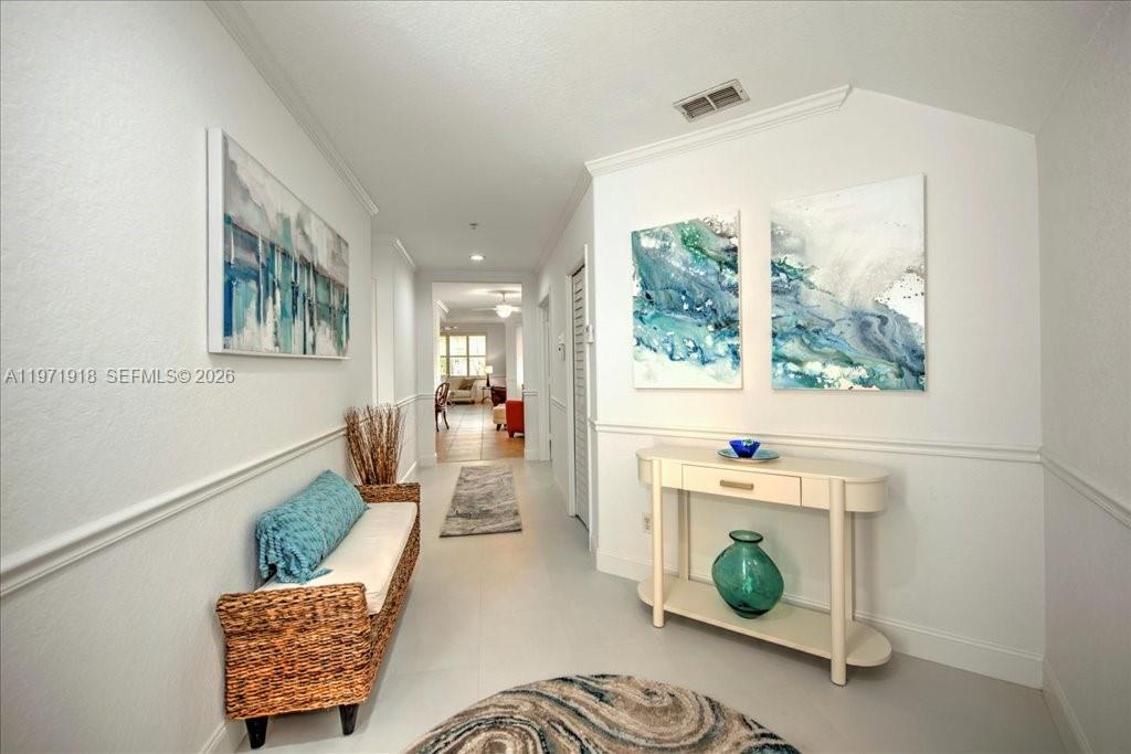 A bright hallway features a wicker bench, a console table, and abstract wall art — 8385 Whisper Trace LN Apt. # 104, Naples FL 34114, NAPLES, FL