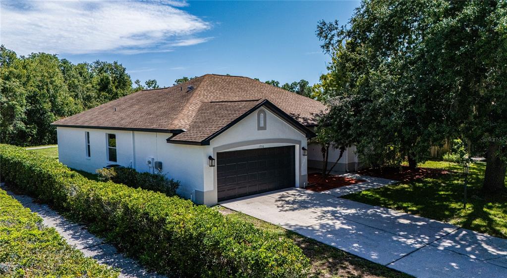 An exterior view of a single-story house with a brown roof and a two-car garage — 1710 BROOKSTONE WAY, PLANT CITY, FL