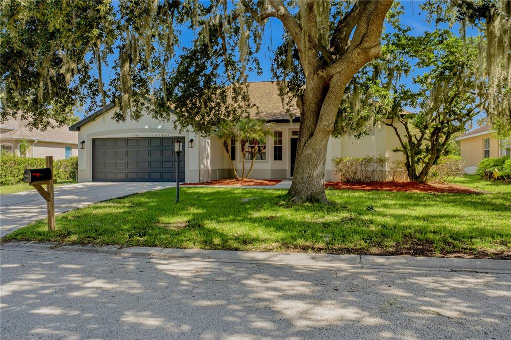 A single-story house with a two-car garage and a large tree in the front yard — 1710 BROOKSTONE WAY, PLANT CITY, FL