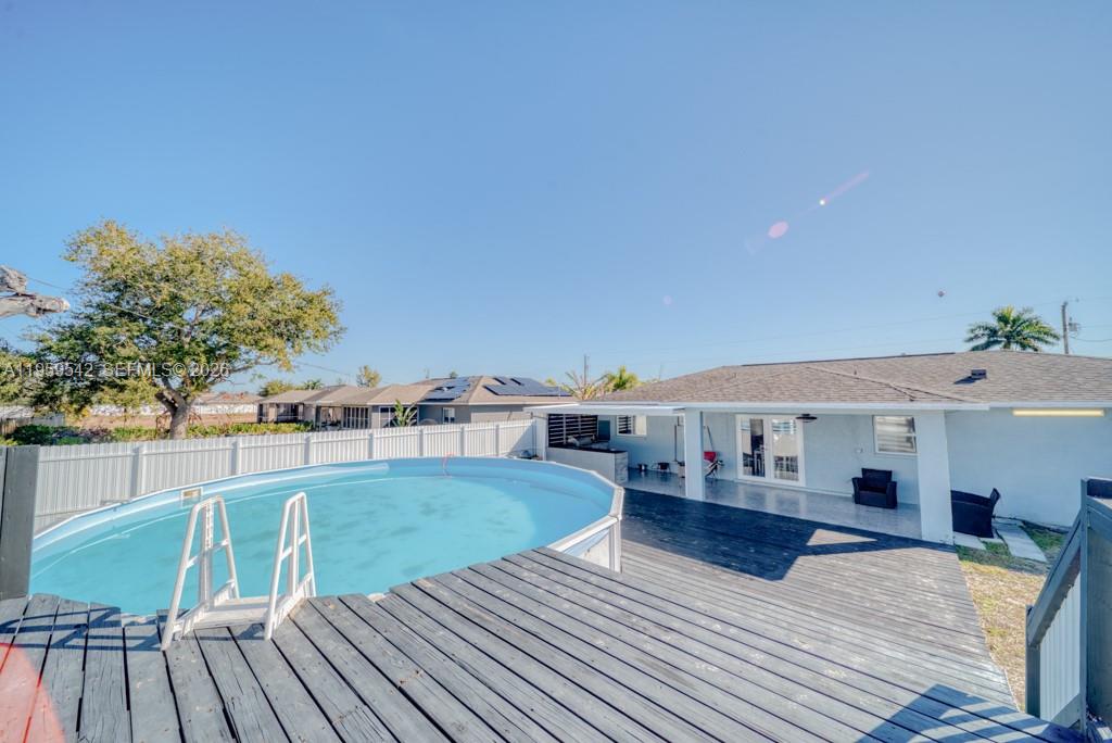 A backyard features a circular above-ground pool, a dark wooden deck, and a single-story house — 1918 SE 5th ct, Cape Coral FL 33990, CAPE CORAL, FL