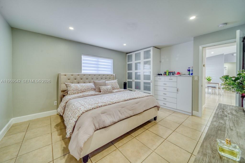 A bedroom features a tufted headboard bed, white wardrobe, dresser, and light-colored tile flooring — 1918 SE 5th ct, Cape Coral FL 33990, CAPE CORAL, FL