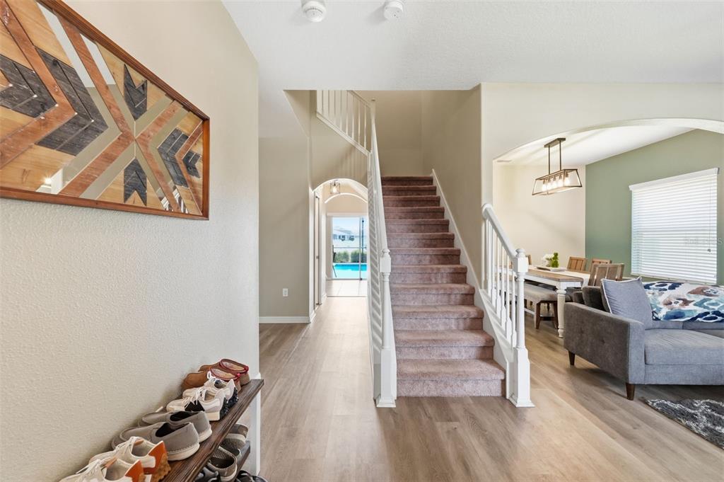 An entryway with a shoe rack, carpeted stairs, and a view toward a backyard pool — 2443 DOVESONG TRACE DRIVE, RUSKIN, FL