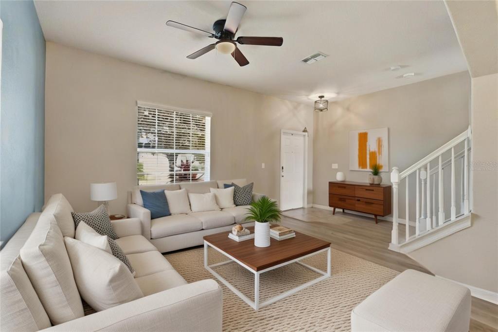 A living room features a white sofa, a wooden coffee table, and a staircase — 2443 DOVESONG TRACE DRIVE, RUSKIN, FL