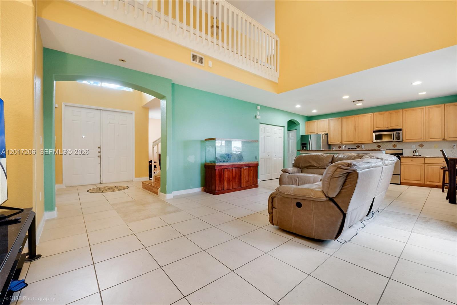 A living room features a large fish tank, beige leather sofa, and light-colored tile flooring — 1402 SE 16th Ave, Homestead FL 33035, HOMESTEAD, FL