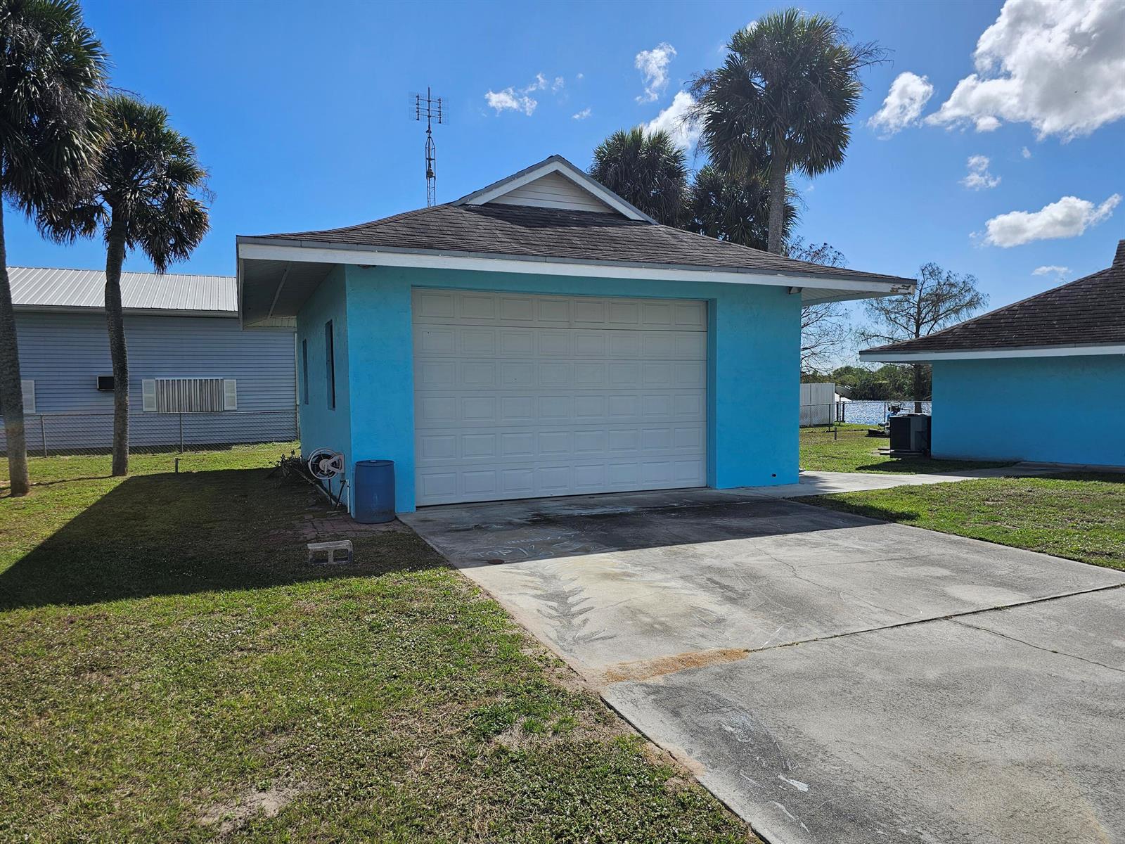 A bright blue detached garage with a white door sits on a grassy lot — 13578 SW 144th Parkway, Okeechobee FL 34974, OKEECHOBEE, FL