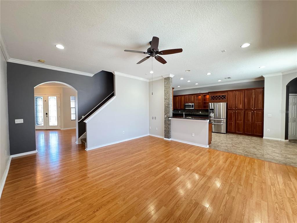An open-concept living area with hardwood floors, a staircase, and a kitchen with dark cabinetry — 23307 ABERCORN LANE, LAND O LAKES, FL