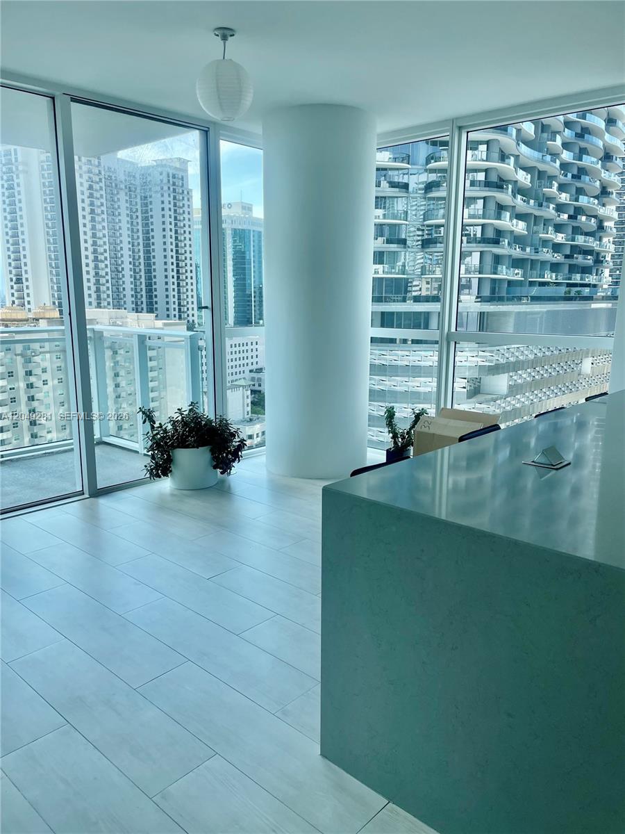 A modern room features floor-to-ceiling windows, light-colored tile flooring, and a central structural column — 1080 Brickell Ave # 1709, Miami FL 33131, MIAMI, FL