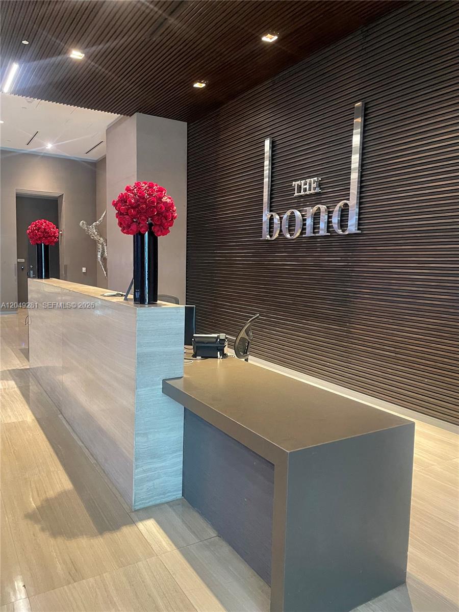 A modern reception desk with red floral arrangements sits in front of a slatted wall — 1080 Brickell Ave # 1709, Miami FL 33131, MIAMI, FL