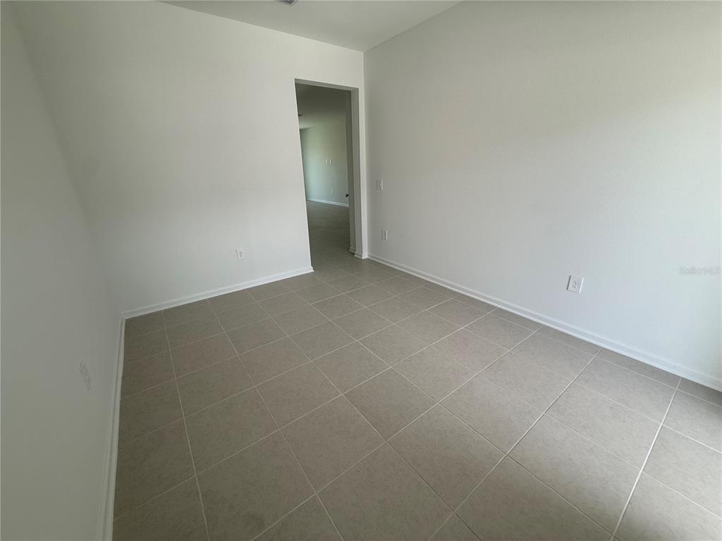 An empty room with white walls, tile flooring, and a doorway leading to another area — 2563 SKYLINE LOOP, KISSIMMEE, FL
