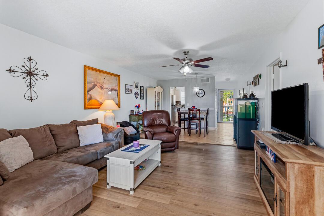 A living room with wood-look flooring, a brown sectional, a recliner, and an adjacent dining area — 1975 SW Palm City Road # G, Stuart FL 34994, STUART, FL