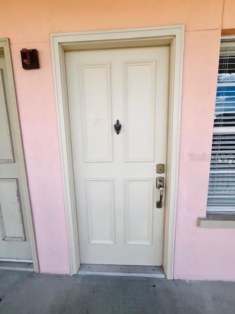 An exterior hallway features orange walls, two beige doors numbered 220 and 230, and windows — 606 MARKET STREET UNIT 230, CELEBRATION, FL