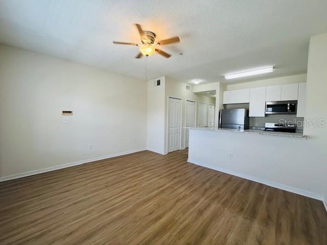 An open-concept living area features wood-look flooring, a ceiling fan, and an adjacent kitchen — 606 MARKET STREET UNIT 230, CELEBRATION, FL