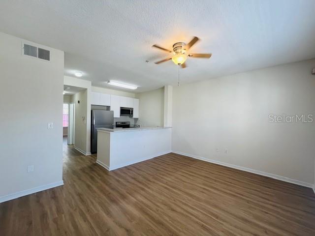 An open-concept living room features light wood-look flooring and a kitchen with a breakfast bar — 606 MARKET STREET UNIT 230, CELEBRATION, FL