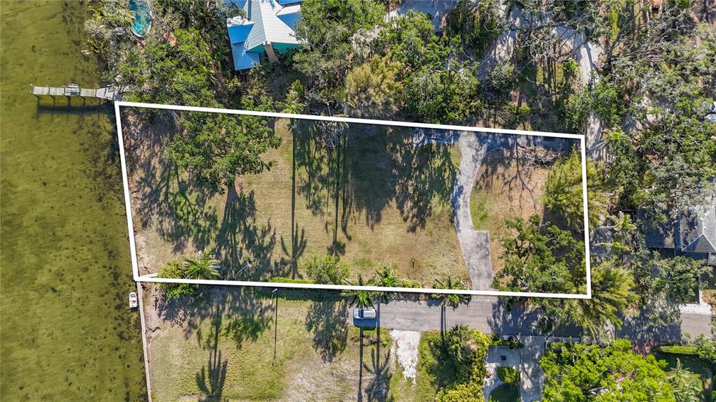 An aerial view shows a vacant waterfront lot with a driveway and mature trees — 408 31ST STREET NW, BRADENTON, FL