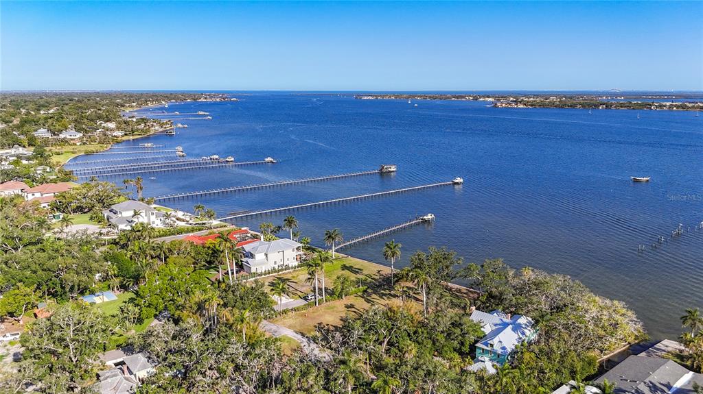 An aerial view shows waterfront homes with long private docks extending into a large bay — 408 31ST STREET NW, BRADENTON, FL