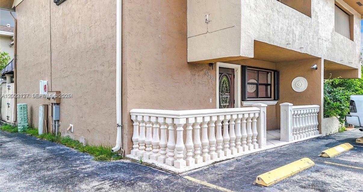 The exterior of a tan building features a white balustrade railing and a front door — 5350 W 26th Ave # 118, Hialeah FL 33016, HIALEAH, FL