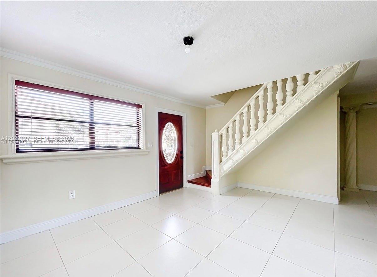 A room with white tile floors, a staircase with white balusters, and a front door — 5350 W 26th Ave # 118, Hialeah FL 33016, HIALEAH, FL