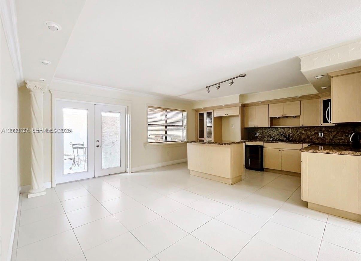 An open-concept kitchen and living area features light-colored cabinetry, granite countertops, and tile flooring — 5350 W 26th Ave # 118, Hialeah FL 33016, HIALEAH, FL