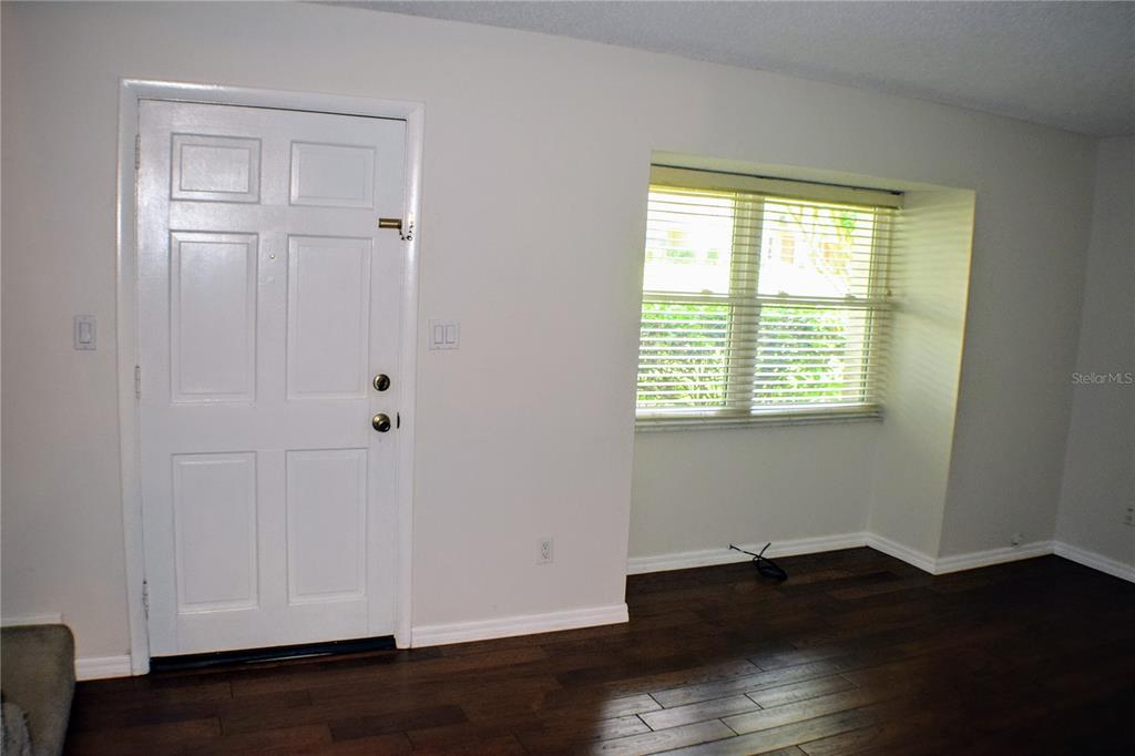 A room with a white door, a window with blinds, and dark wood flooring — 814 PARK LAKE CIRCLE UNIT 8, MAITLAND, FL