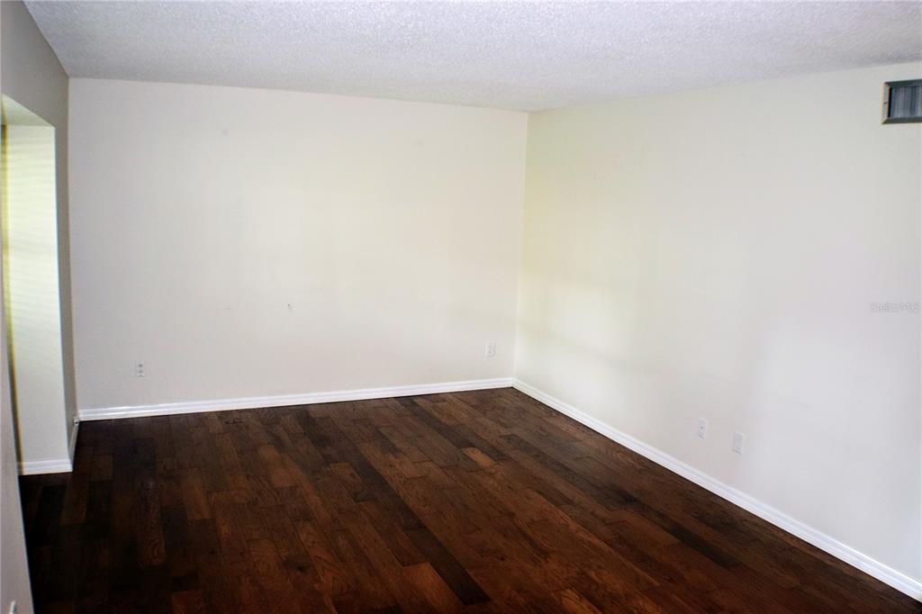 An empty room features dark hardwood flooring, off-white walls, and a textured white ceiling — 814 PARK LAKE CIRCLE UNIT 8, MAITLAND, FL