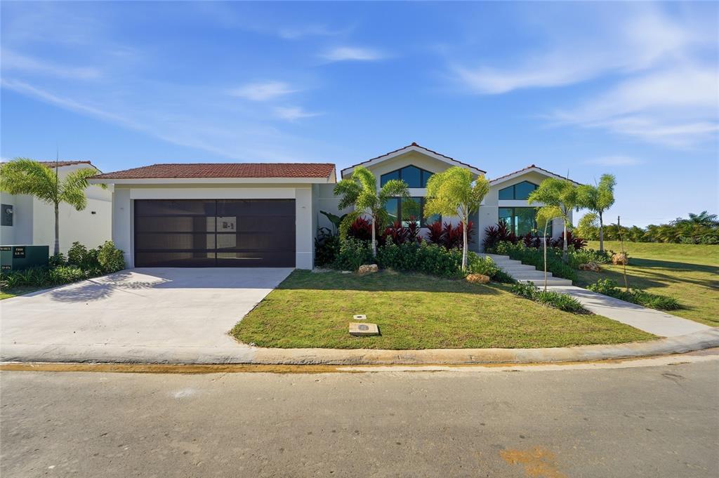 A modern single-story house with a two-car garage, tiled roof, and landscaped front yard — 804 CAMINO DE LAS VERBENAS, DORADO, PR