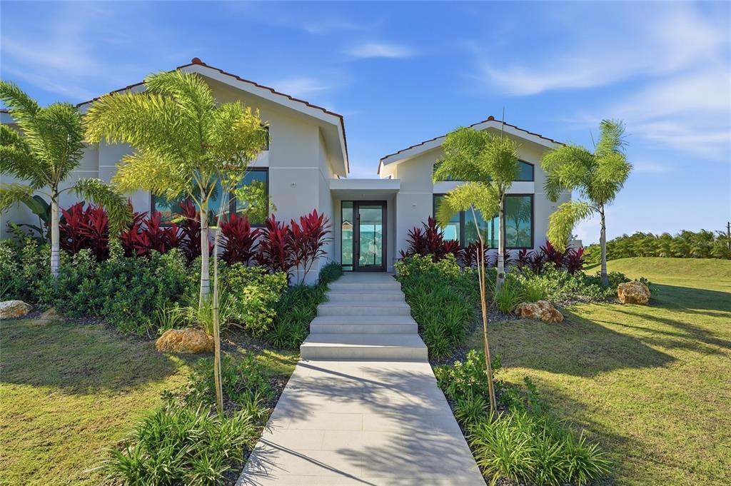 A modern house with a tiled roof, palm trees, and a concrete walkway leading to entry — 804 CAMINO DE LAS VERBENAS, DORADO, PR