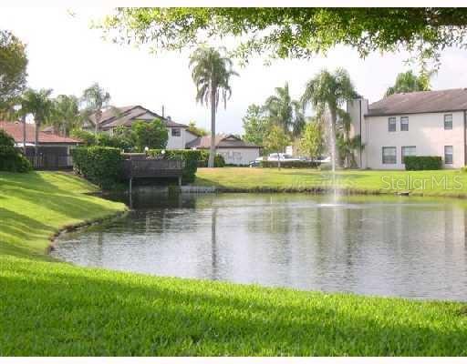 A pond with a fountain sits in front of apartment buildings and palm trees — 3739 59TH AVENUE W UNIT 3739, BRADENTON, FL