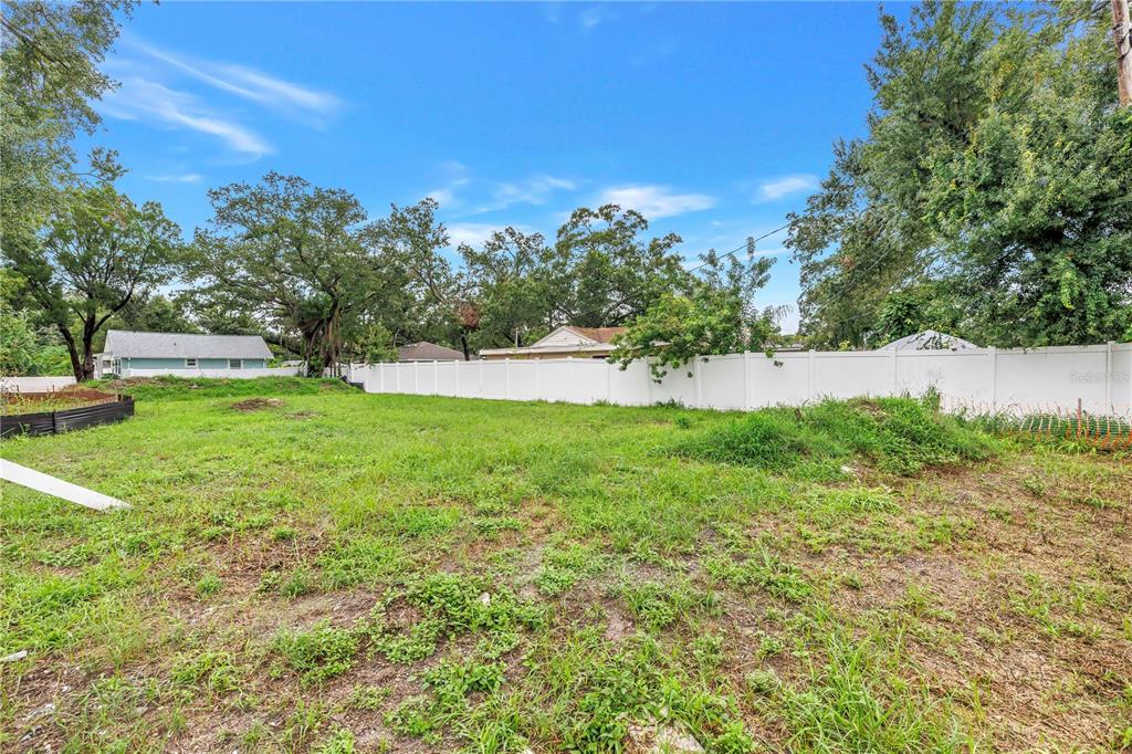 A vacant, grassy residential lot enclosed by a white vinyl fence with surrounding trees — 6401 29TH STREET N, ST PETERSBURG, FL