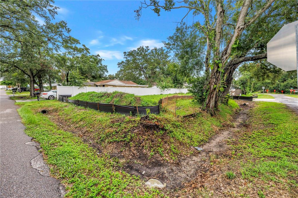 A vacant corner lot features a drainage ditch, silt fencing, and mature trees — 6401 29TH STREET N, ST PETERSBURG, FL