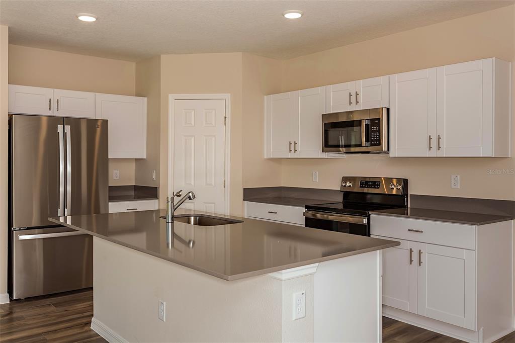 A kitchen with white cabinets, stainless steel appliances, and a large central island — 5394 SAN PIETRO DRIVE, WINTER HAVEN, FL