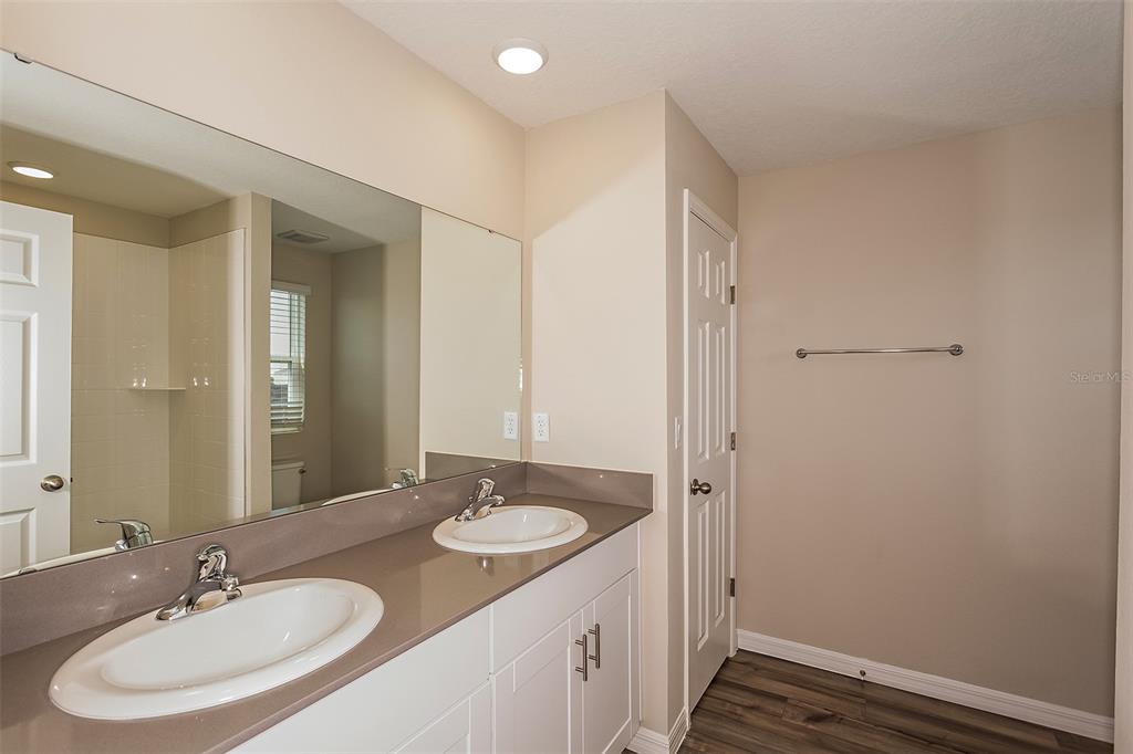 A bathroom features a double vanity with a brown countertop and white cabinets — 5394 SAN PIETRO DRIVE, WINTER HAVEN, FL