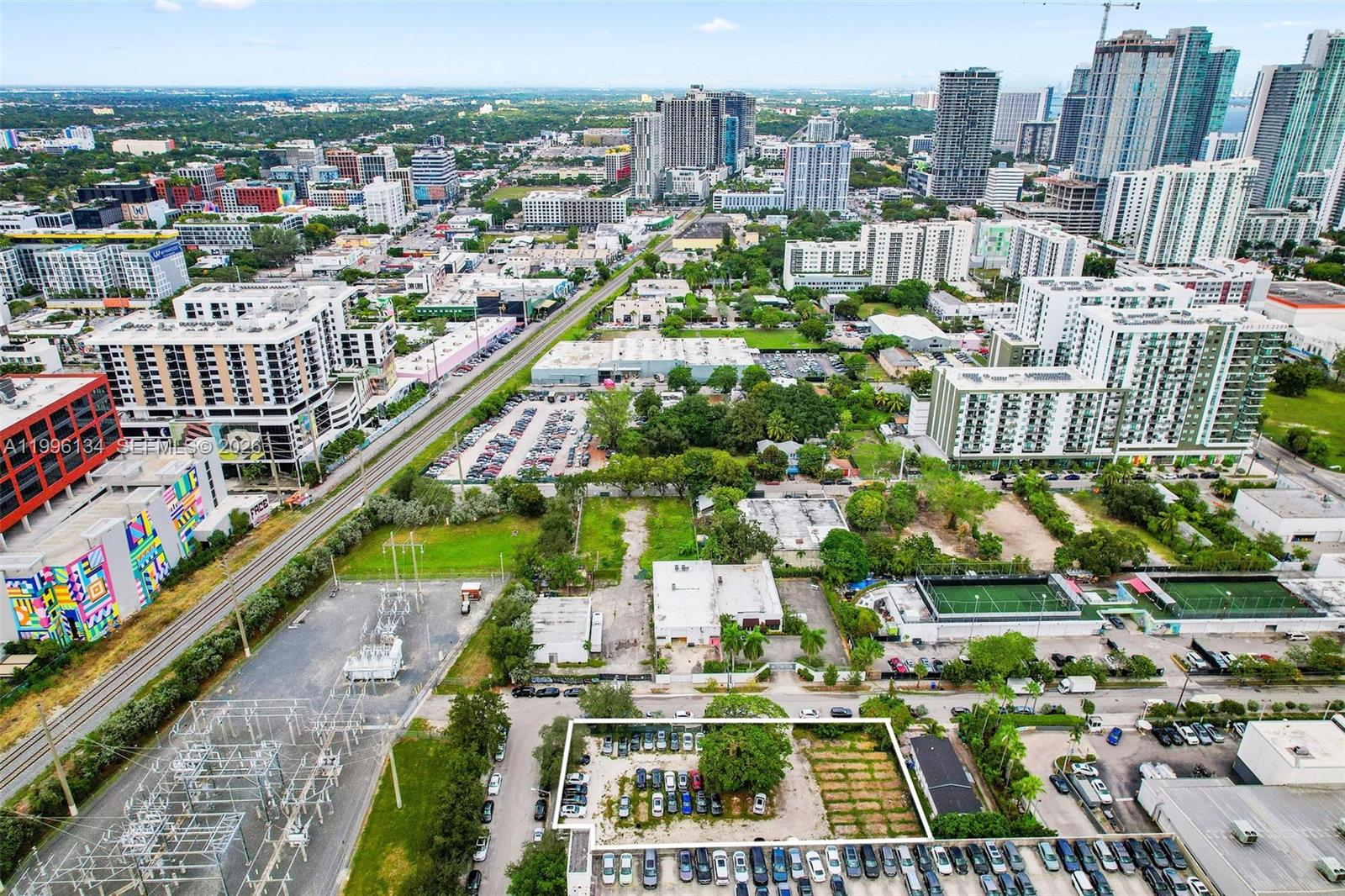 An aerial view shows a city landscape with a highlighted vacant lot and parking area — 100 NE 21st St, Miami FL 33137, MIAMI, FL