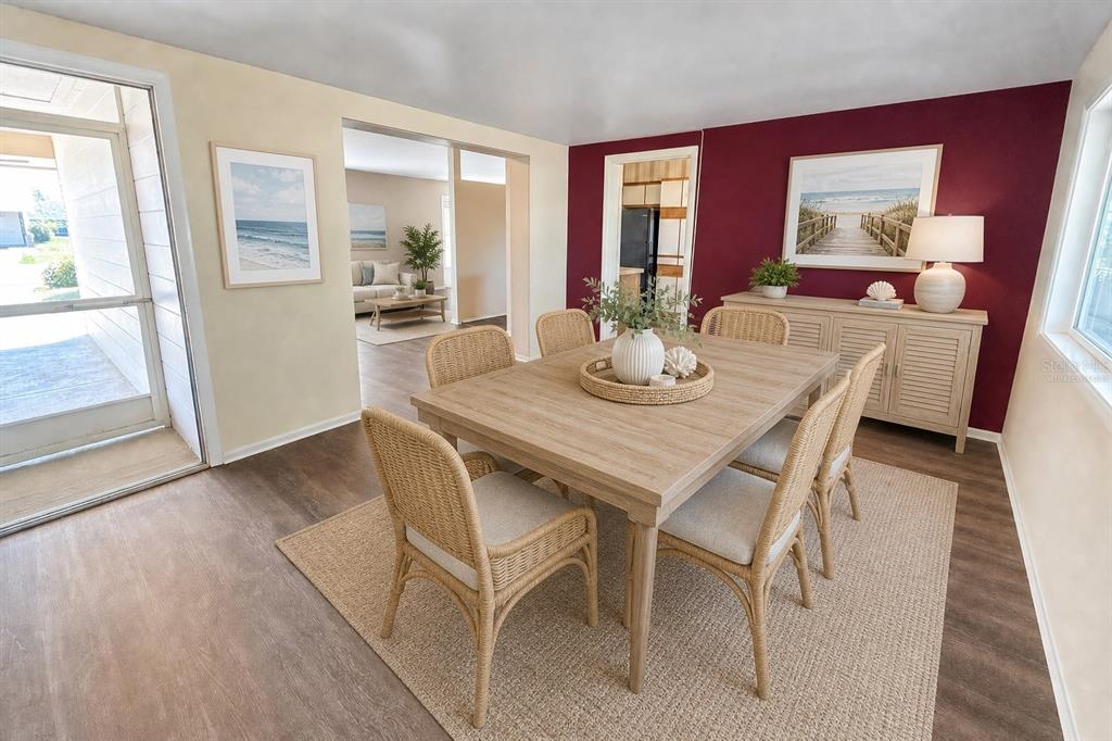 A dining room with a wooden table, wicker chairs, and a deep red accent wall — 1515 ARROWHEAD DRIVE, SUN CITY CENTER, FL
