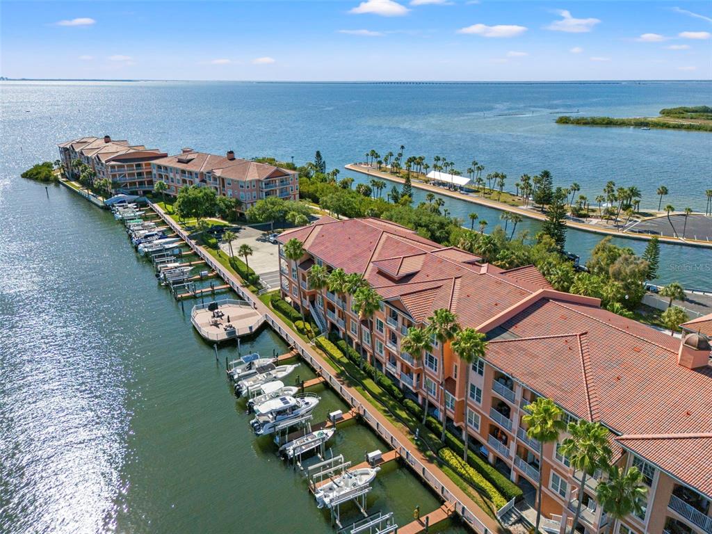 An aerial view shows waterfront apartment buildings with a private marina and boat slips — 5000 CULBREATH KEY WAY UNIT 1-107, TAMPA, FL