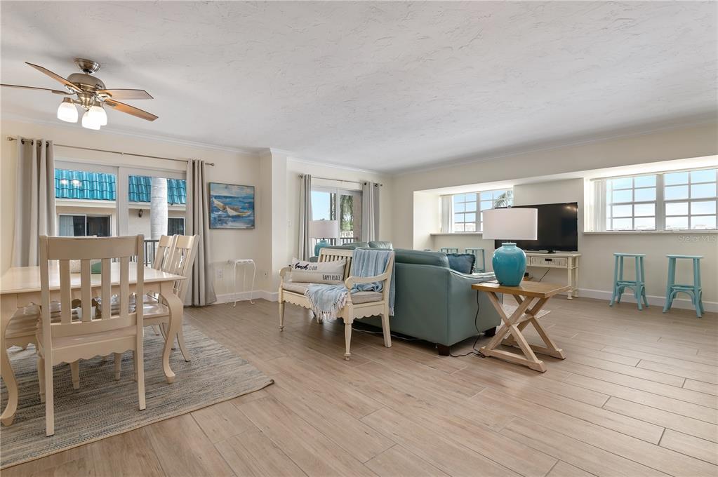 A living and dining area with light wood-look tile flooring and a ceiling fan — 5963 MIDNIGHT PASS ROAD UNIT 332, SARASOTA, FL