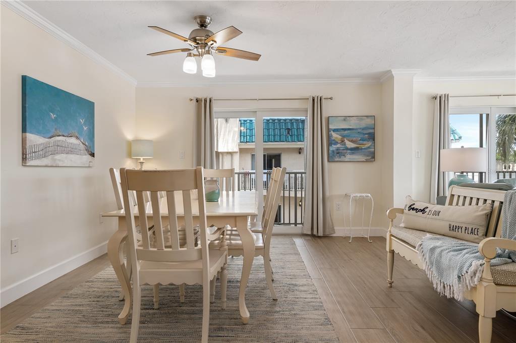 A dining area features a wooden table, chairs, a ceiling fan, and a sliding glass door — 5963 MIDNIGHT PASS ROAD UNIT 332, SARASOTA, FL