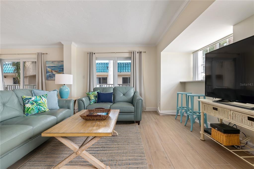 A living room features light blue leather sofas, a wooden coffee table, and a television — 5963 MIDNIGHT PASS ROAD UNIT 332, SARASOTA, FL