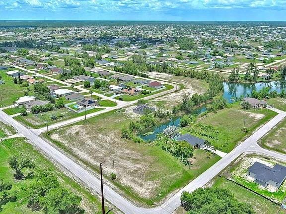 This is an aerial view of a residential neighborhood featuring vacant lots and a canal — 3417 ANDALUSIA BOULEVARD, CAPE CORAL, FL