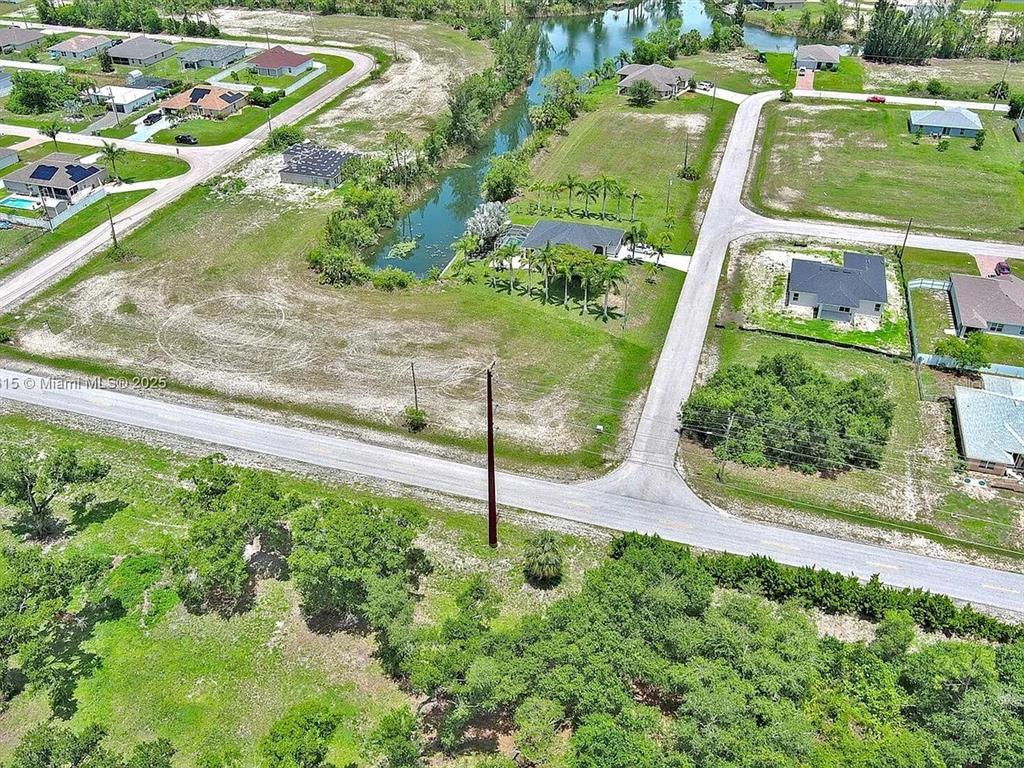 An aerial view shows a residential neighborhood with houses, a canal, and vacant lots — 3417 ANDALUSIA BOULEVARD, CAPE CORAL, FL