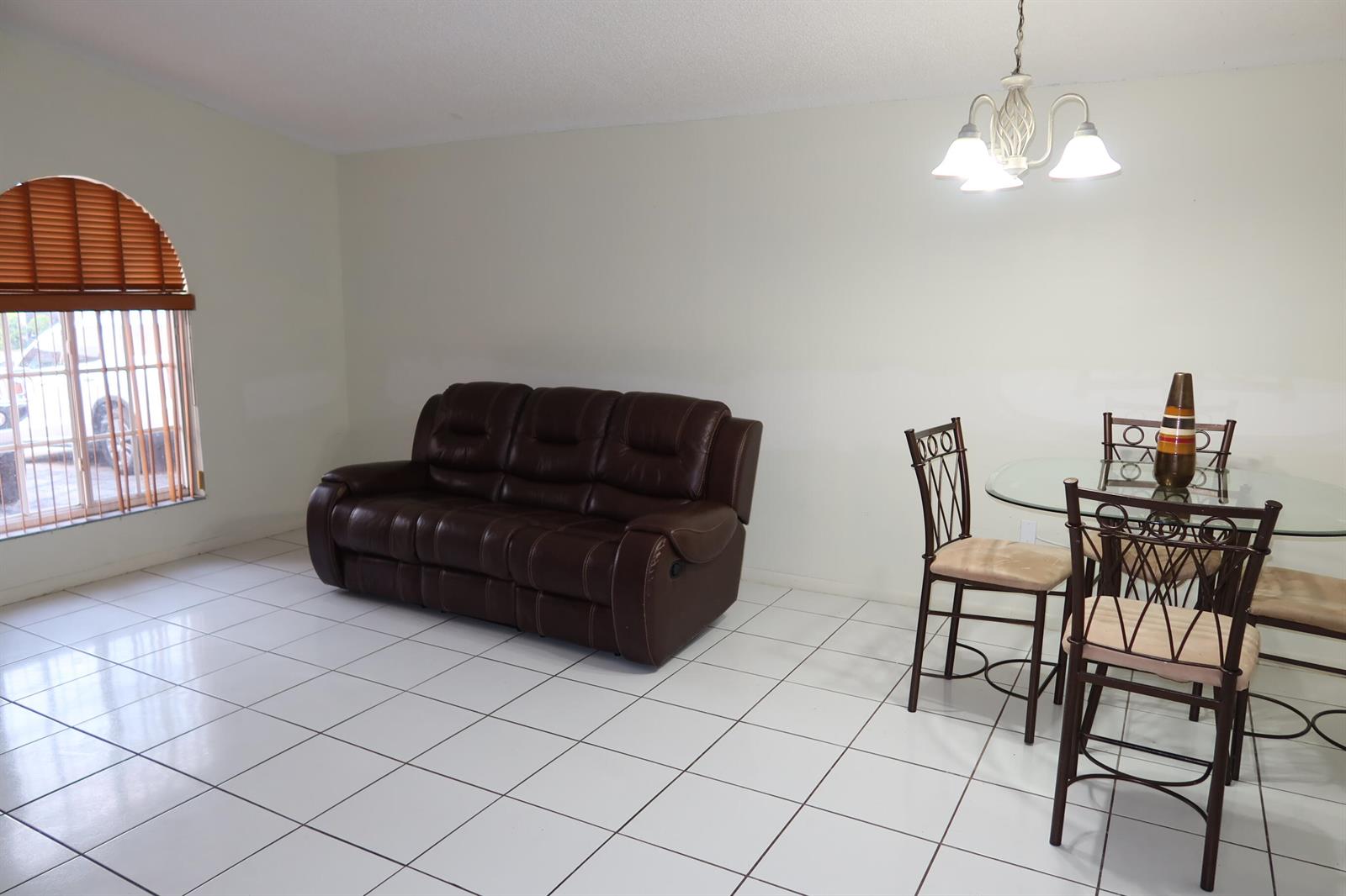 A living and dining area features white tile floors, a brown leather sofa, and furniture — 7001 W 35th Avenue # 273, Hialeah FL 33018, HIALEAH, FL