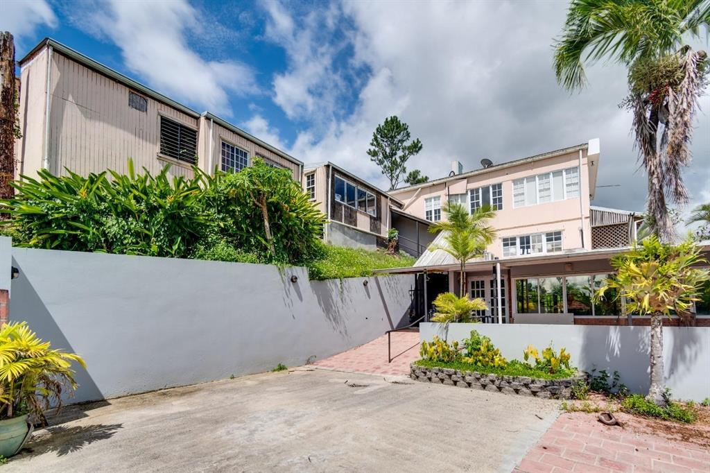 An exterior view of a multi-story house with a concrete driveway and landscaped garden beds — 734 BO ARENAS, CIDRA, PR
