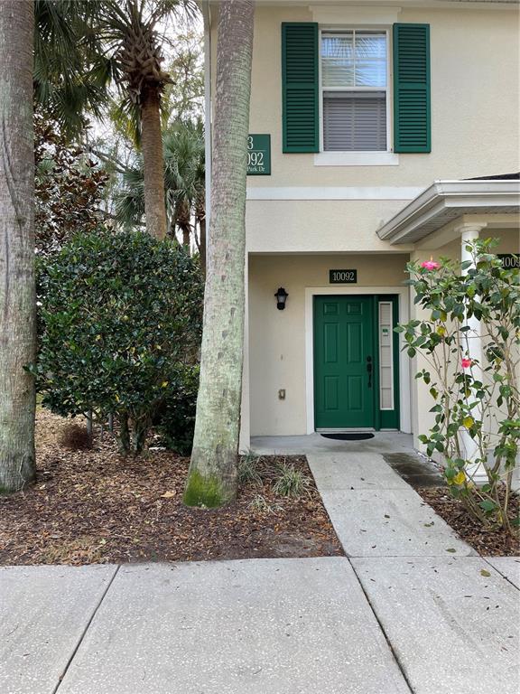 A green front door with a side window is set into a beige two-story building — 10092 REGENT PARK DRIVE UNIT 2301, ORLANDO, FL