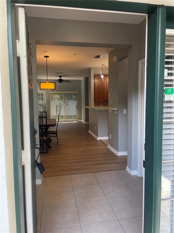 An entryway with tile flooring leads into an open-concept living area with wood-look flooring — 10092 REGENT PARK DRIVE UNIT 2301, ORLANDO, FL