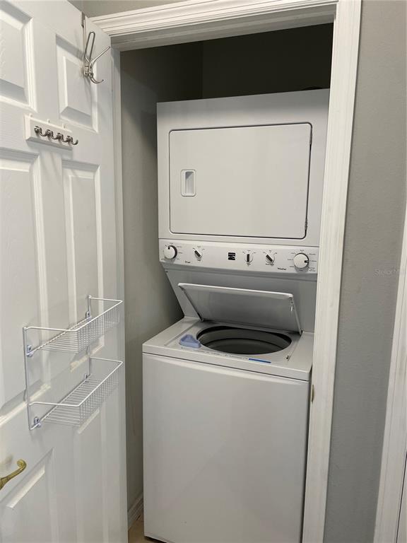 A white stacked washer and dryer unit sits inside a small closet with door storage — 10092 REGENT PARK DRIVE UNIT 2301, ORLANDO, FL