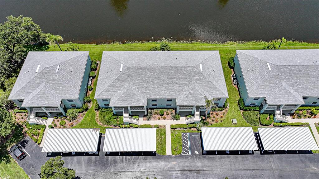 An aerial view shows three apartment buildings with gray roofs situated next to a lake — 5725 GREENWOOD AVENUE UNIT 2101, NORTH PORT, FL