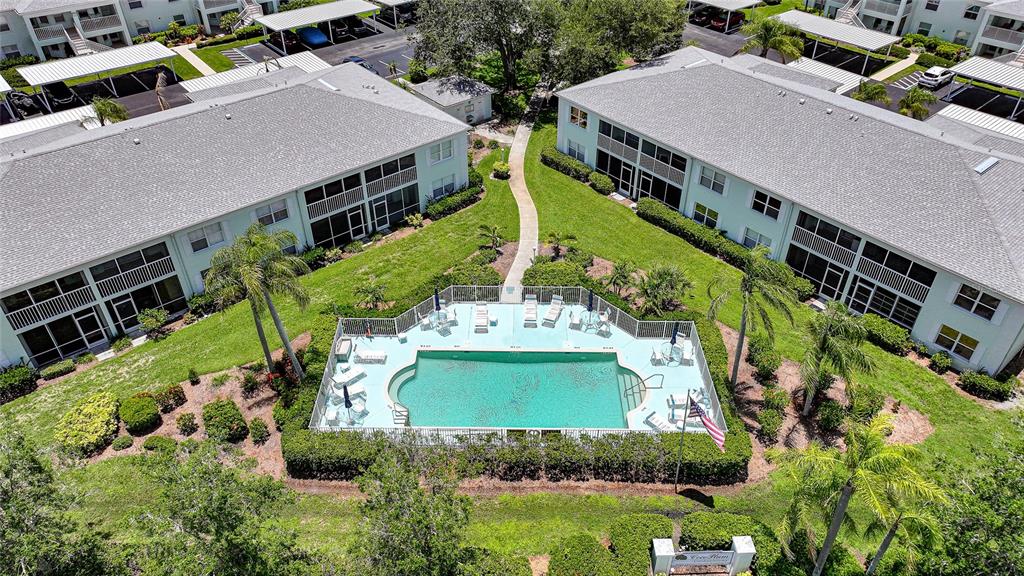 An aerial view shows a swimming pool situated between two apartment buildings with covered parking — 5725 GREENWOOD AVENUE UNIT 2101, NORTH PORT, FL